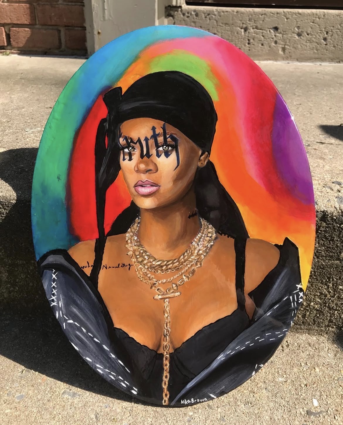 Oval painted portrait with a black headwrap, gold jewelry and rainbow background