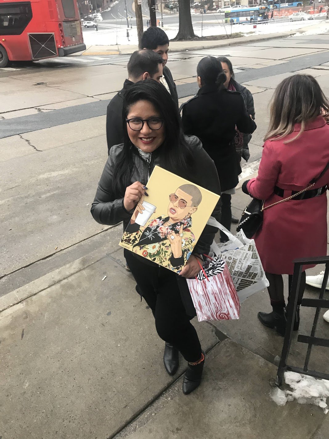 Collector smiling outdoors while holding Nika B’s illustrated portrait of Bad Bunny
