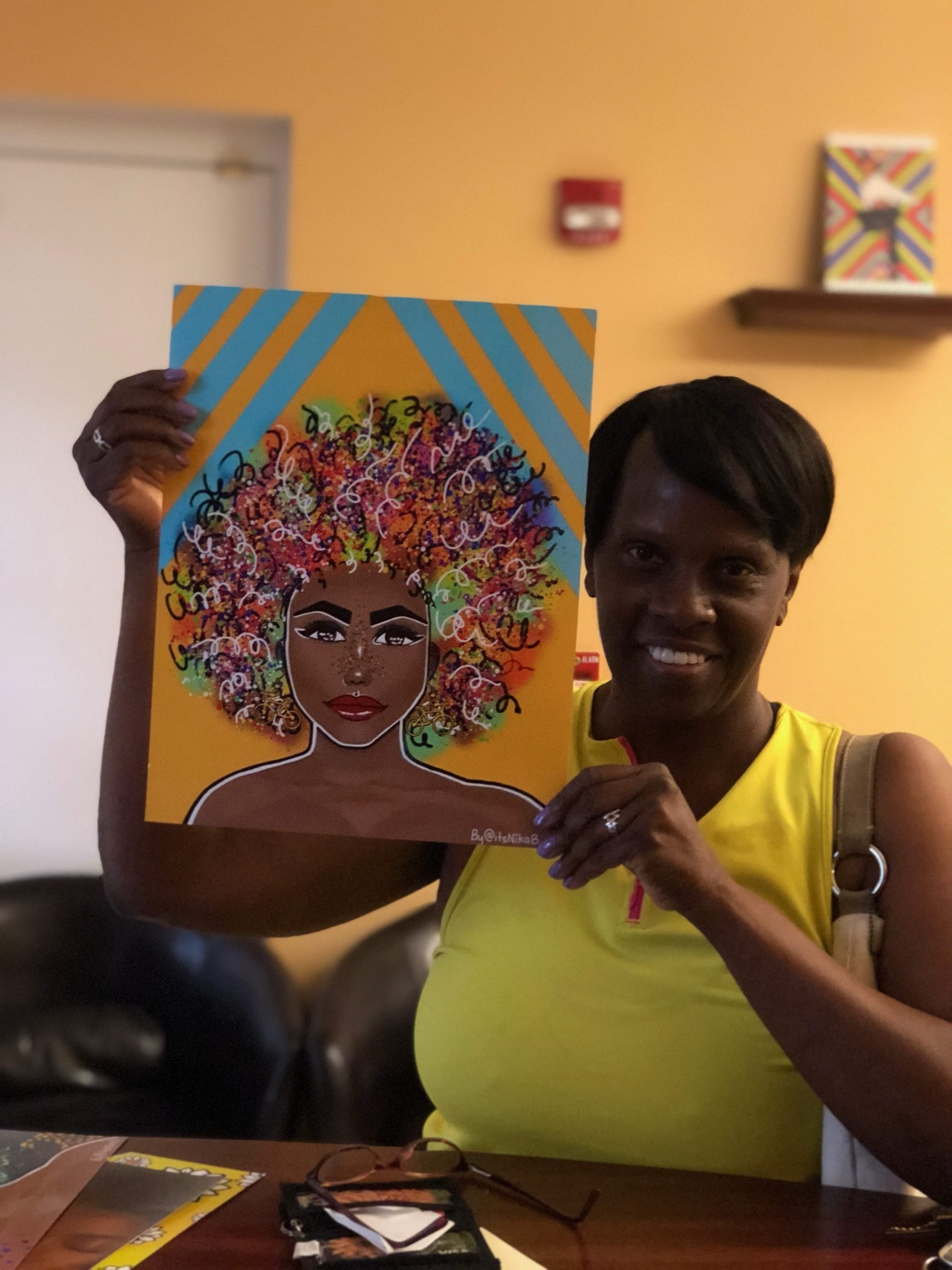 Collector holding Nika B’s portrait with multicolored curls against a yellow and blue background