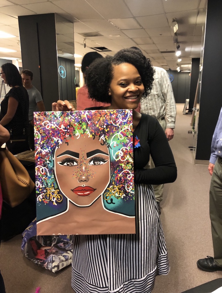 Collector holding Nika B’s colorful curly-haired portrait at an event