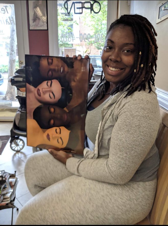 Nika B in a gray outfit holding a commissioned painting of four faces